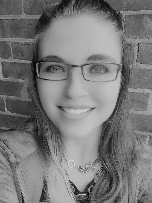 Reiki practitioner portrait—warm smile, brick wall background.