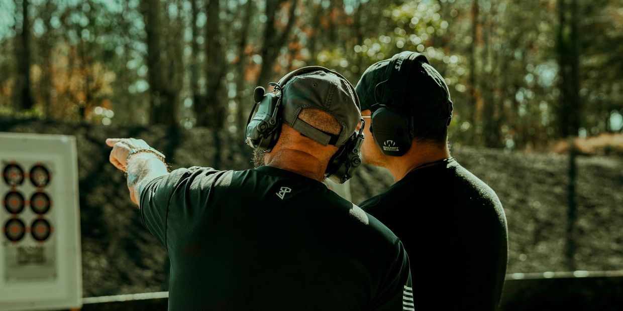 Two men with ear protection at a shooting range.