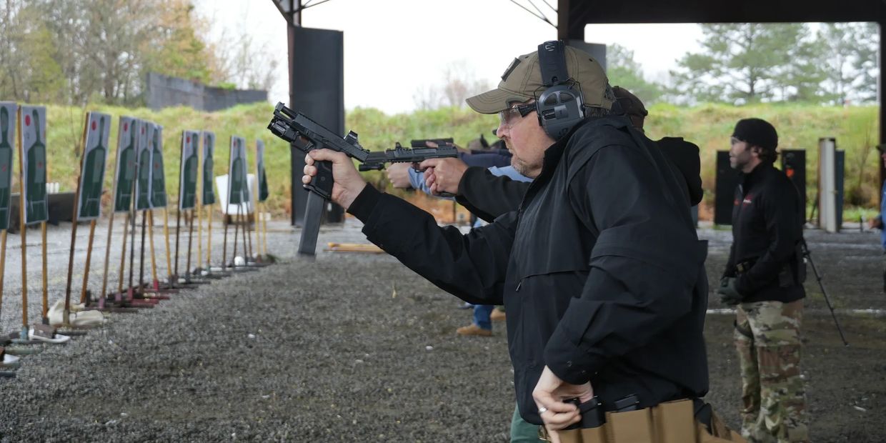 Men firing handguns at a shooting range.
