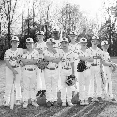 Youth baseball team posing together on field.