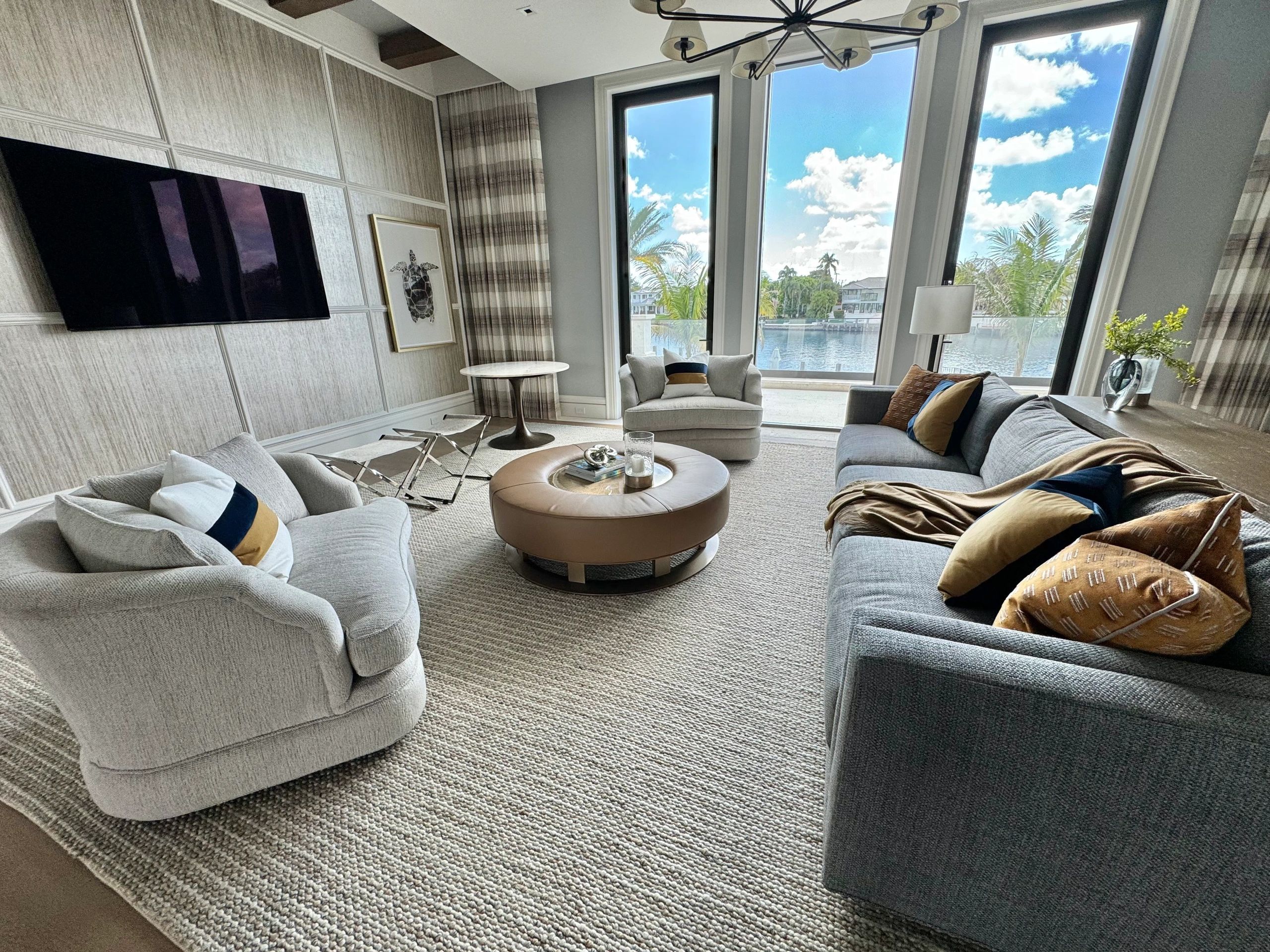 Modern upholstered gray sectional and armchair in a bright, professionally designed living room.