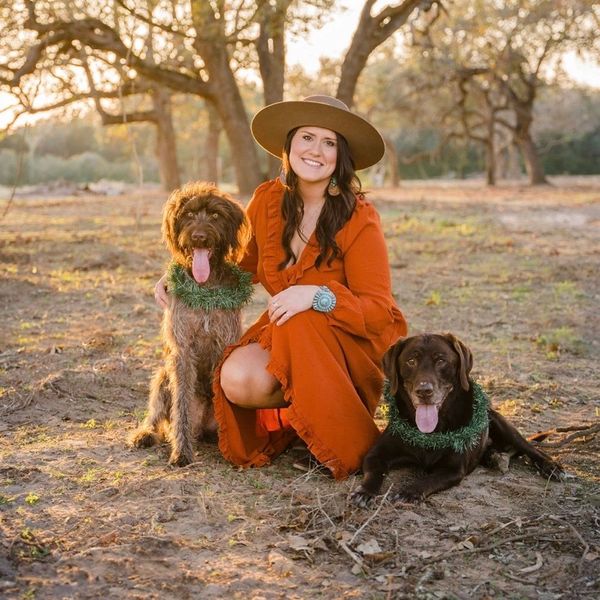 Woman in orange dress with two dogs outdoors.