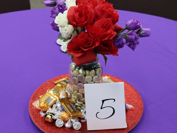 Table centerpiece with flowers, candies, and a table number 5.
