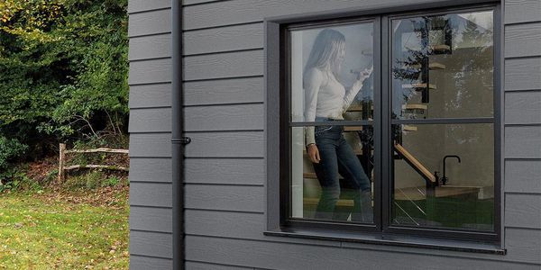 Woman inside a modern house looking out the window.