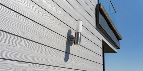 Modern outdoor light fixture on gray siding of a building.