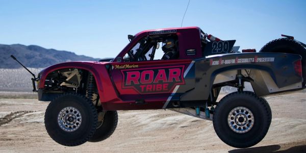 Off-road race truck airborne over desert terrain.