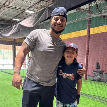 Two people smiling together on an indoor artificial turf field.