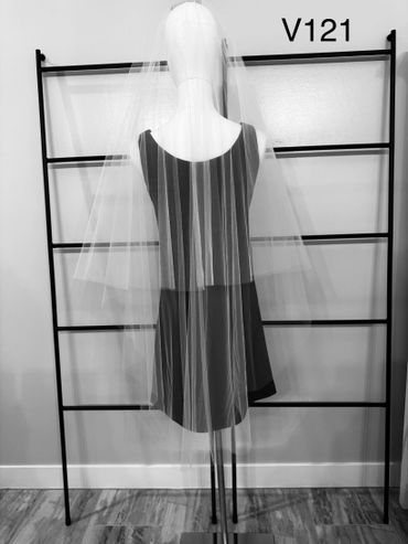 Mannequin wearing a sheer bridal veil against a black rack.