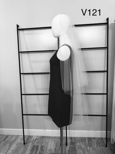 Mannequin wearing a black dress and a long, sheer bridal veil.