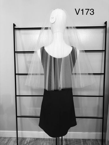 Mannequin displaying a black dress with a long veil against a simple backdrop.