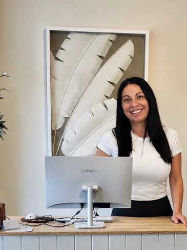 Woman smiling behind a computer at a desk.