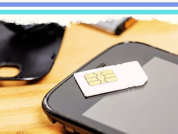 A SIM card placed on a smartphone with a SIM tray nearby.