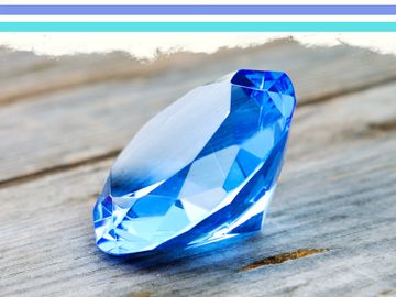 A sparkling blue gemstone resting on a wooden surface.