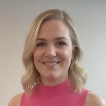 Smiling woman with blonde hair wearing a pink sleeveless top.