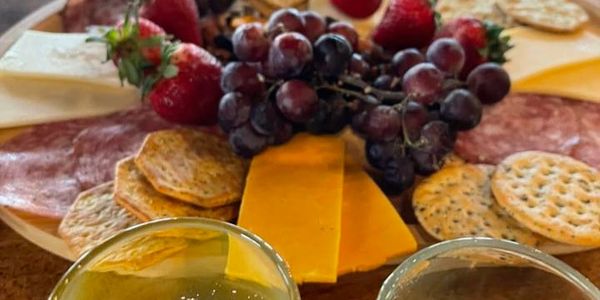 A charcuterie board with cheese, crackers, grapes, and strawberries.