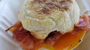 Breakfast sandwich with bacon and egg on an English muffin.