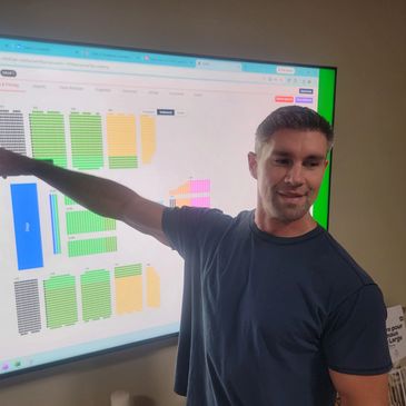 Man pointing at colorful charts on a large screen.