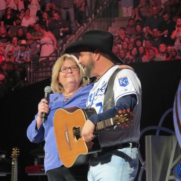 Man and woman sharing a moment on stage with a guitar.