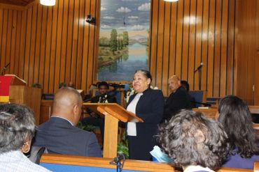 Woman speaking at a podium in a church with an attentive audience.