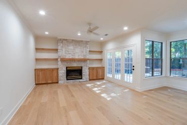 Empty living room with fireplace and large windows.