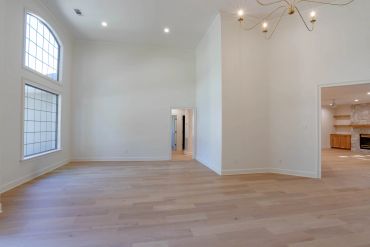 Bright empty room with wooden floors and large window.