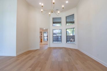 Empty room with wood flooring and chandelier.