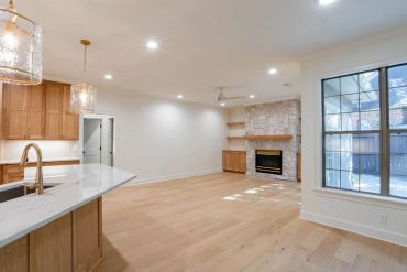 Spacious modern living room with kitchen and fireplace.