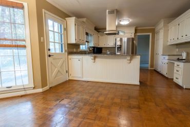Spacious kitchen with wooden floor and white cabinets.