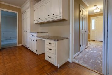 Empty kitchen with white cabinets and a tiled floor.