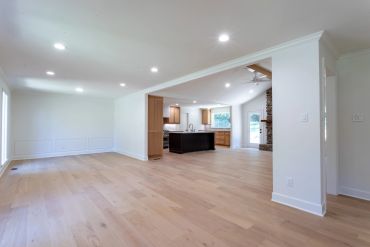 Empty modern open-concept living and kitchen area with wooden floors.