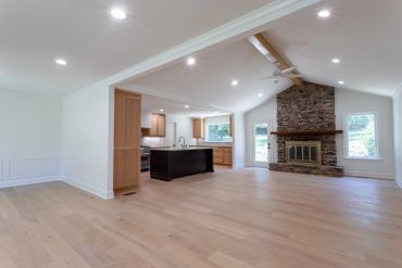Spacious living room with wooden floors and stone fireplace.