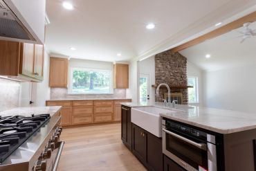 Modern kitchen with wooden cabinets and a large stone fireplace.