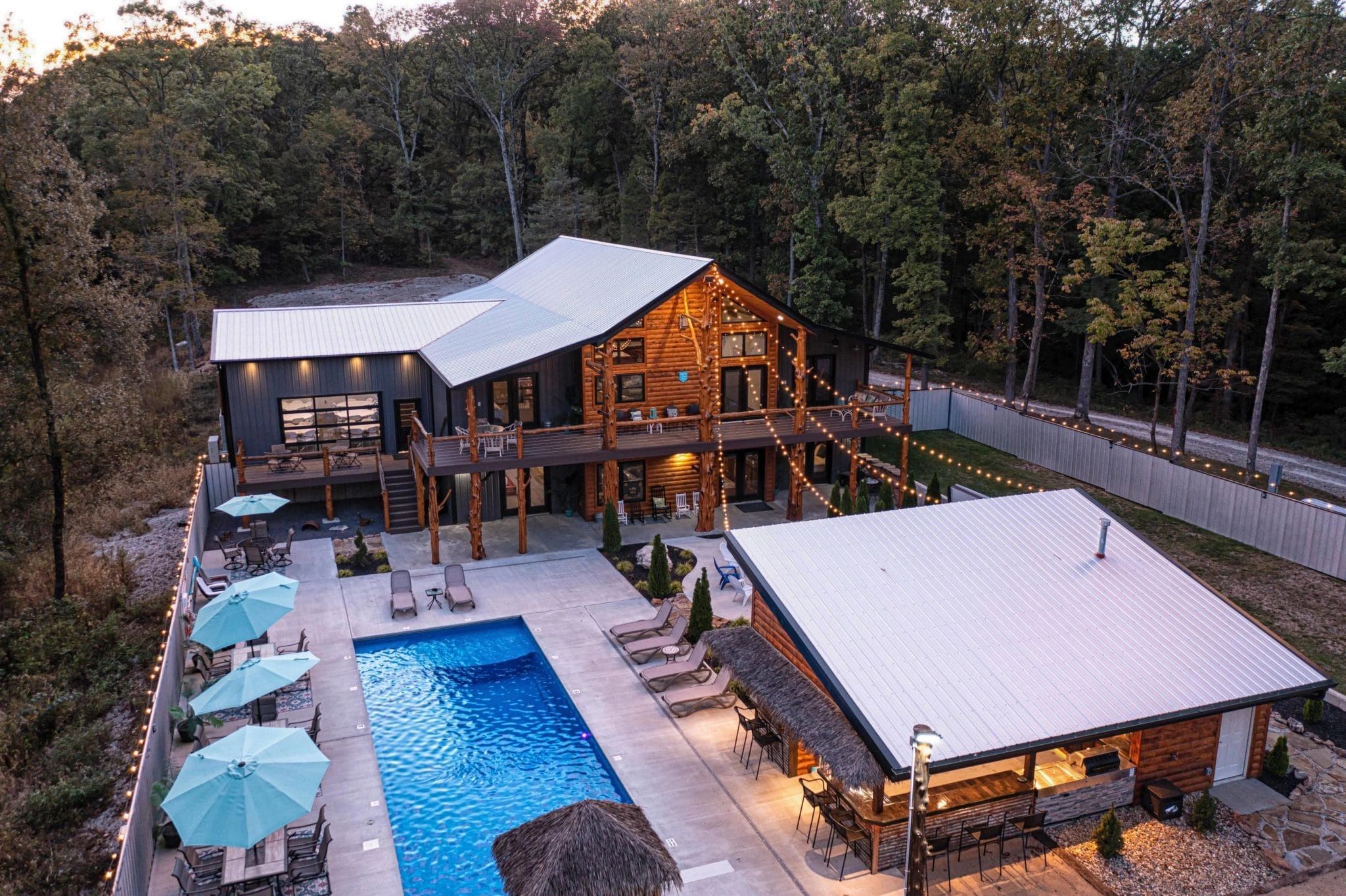 A cozy cabin with a swimming pool and outdoor seating at dusk.