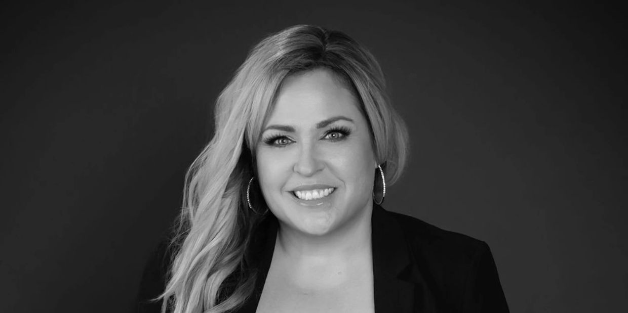 Smiling woman wearing a black blazer and lace top.