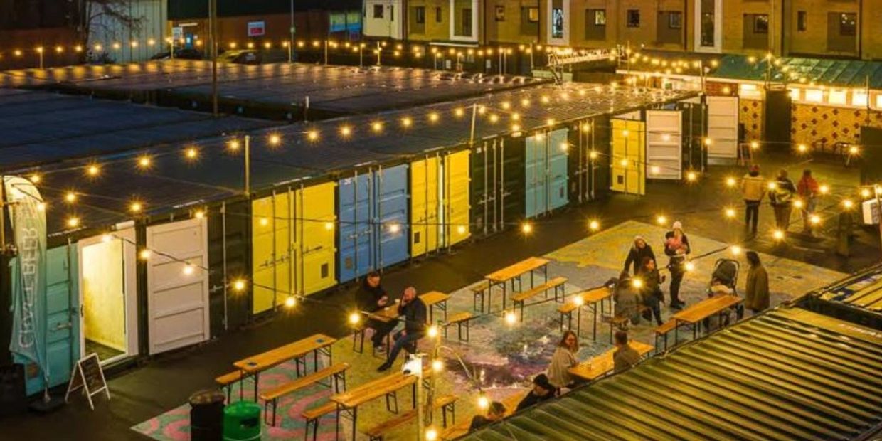 St Saviours Yard showing people drinking beneath twinkling lights along side a row of shipping conta