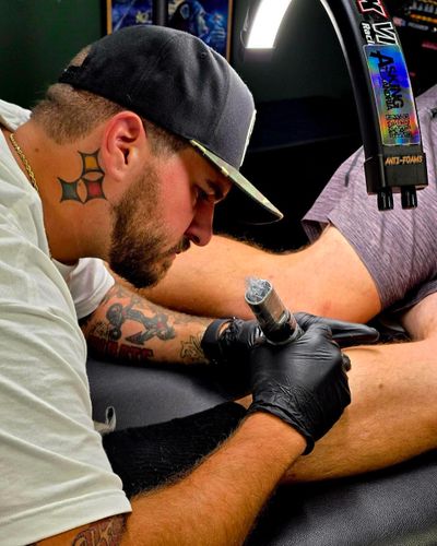 Tattoo artist focused on inking a client's leg in a studio.