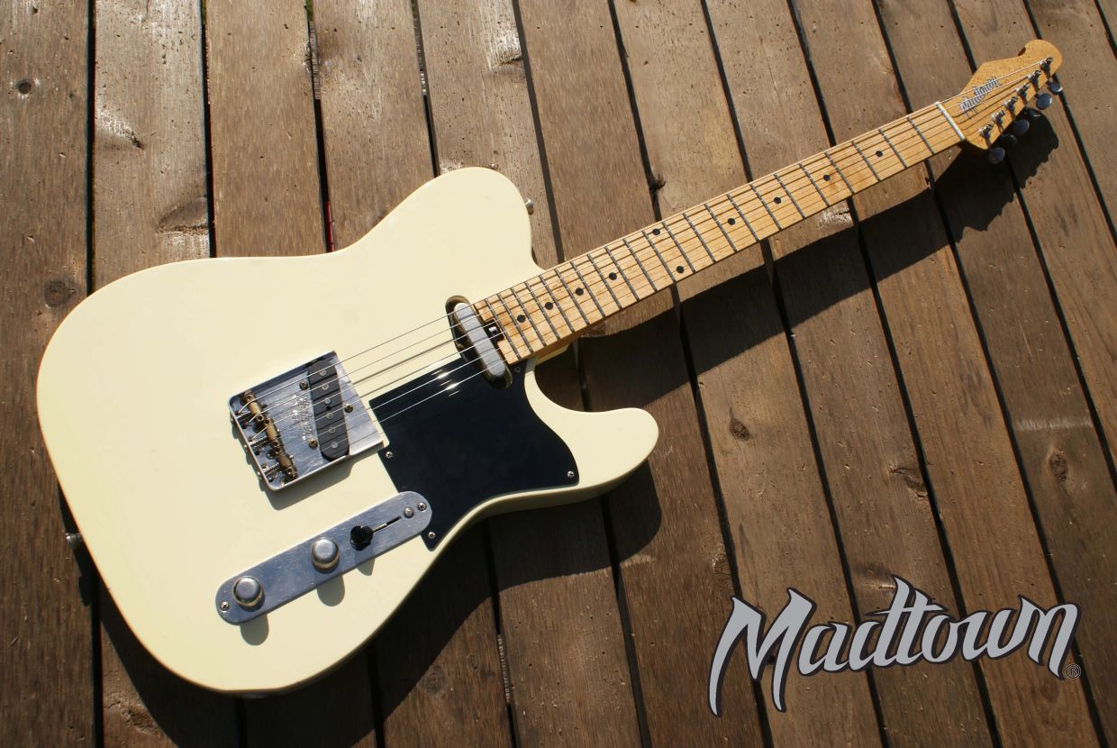 White electric guitar on wooden floor.