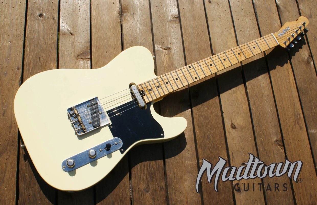 Cream electric guitar on wooden floor.