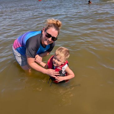 A woman and child enjoy a sunny day in the water with life jacket safety.