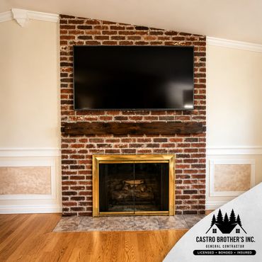Brick fireplace with a mounted TV and wooden mantel in a cozy living room.