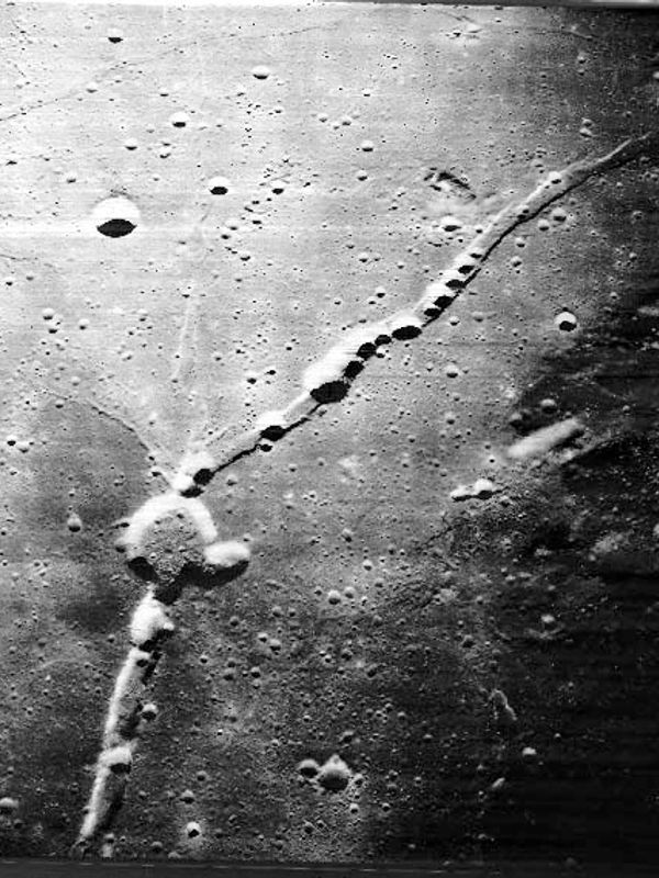 Long, thin crater chain on a cratered lunar surface.