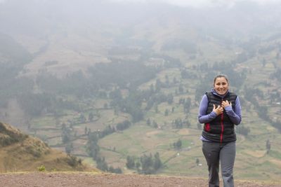 A woman smiling happily on a misty mountain trail.