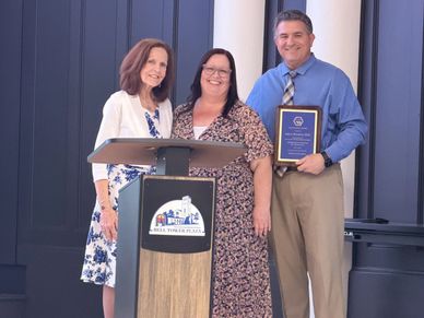 Three people posing at a podium, one holding a plaque.