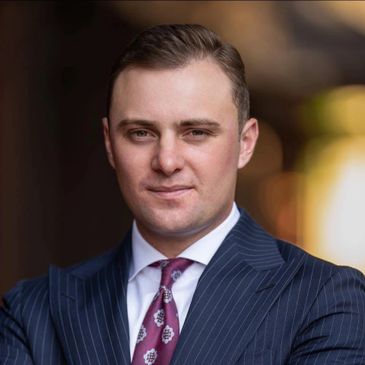 Confident young man in a sharp pinstripe suit and patterned tie.