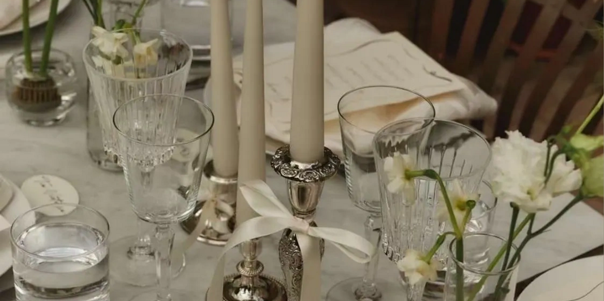 Elegant table setting with candles, glassware, and white flowers.