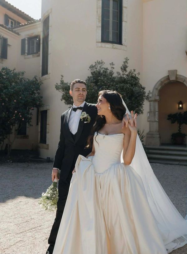 Newlywed couple in elegant wedding attire outside a historic building.