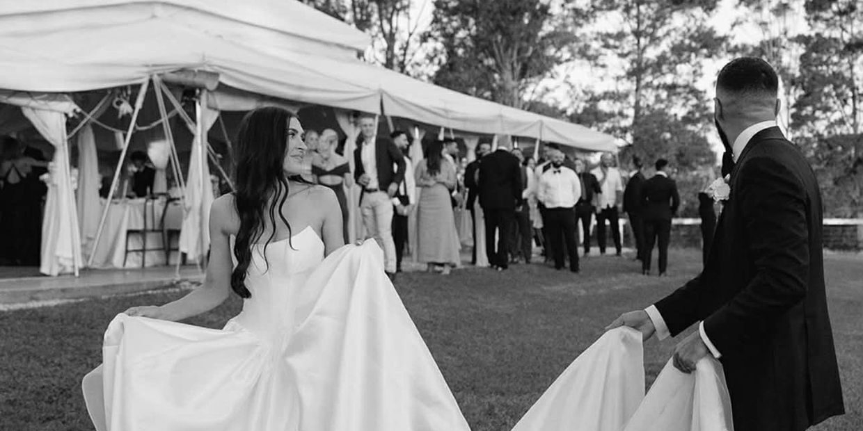 Bride and groom sharing a joyful moment outside a wedding tent.