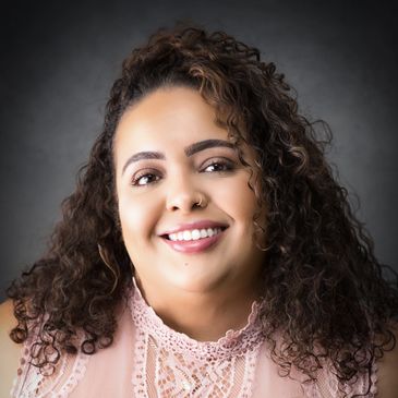 Smiling woman with curly hair in a lace top.