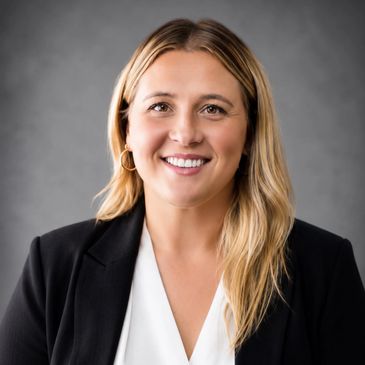 Smiling woman in business attire with a gray background.