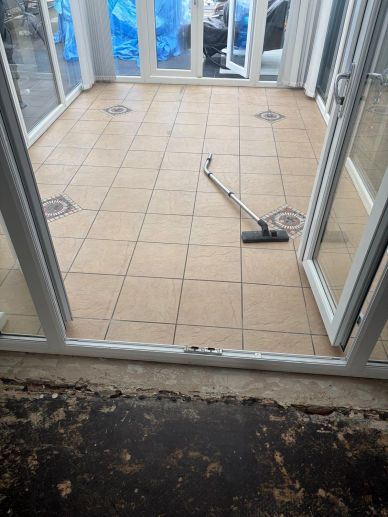 Vacuum cleaner on tiled floor in a room with glass doors.